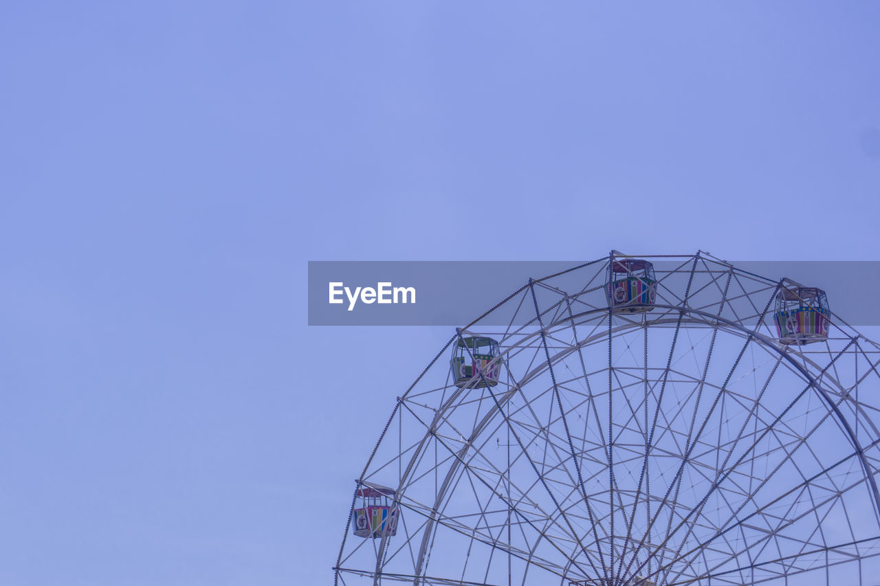 Low angle view of ferris wheel against blue sky