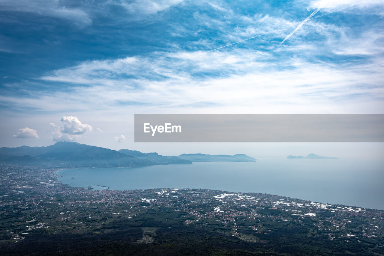 Aerial view of land by sea against sky