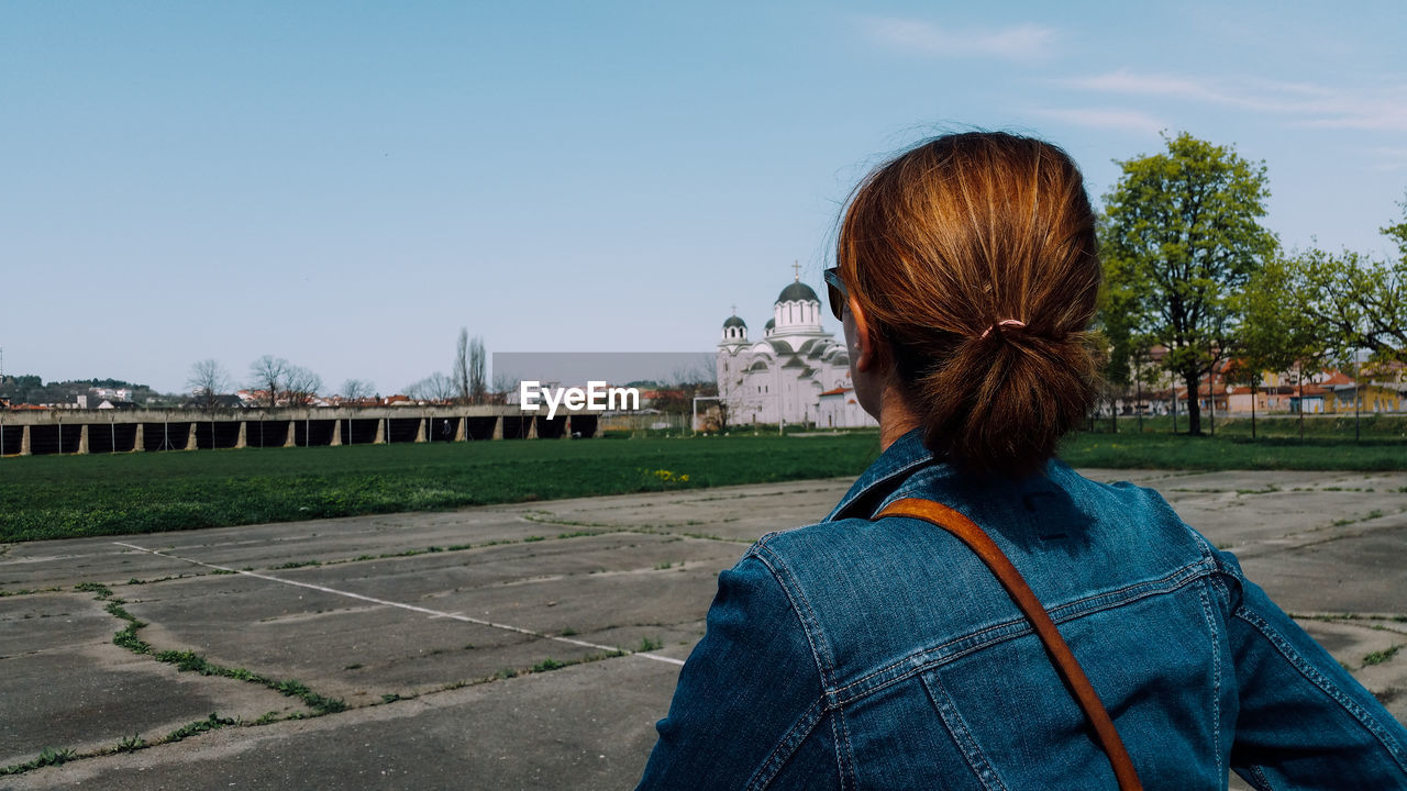 Woman looking at blue sky while standing by sport court