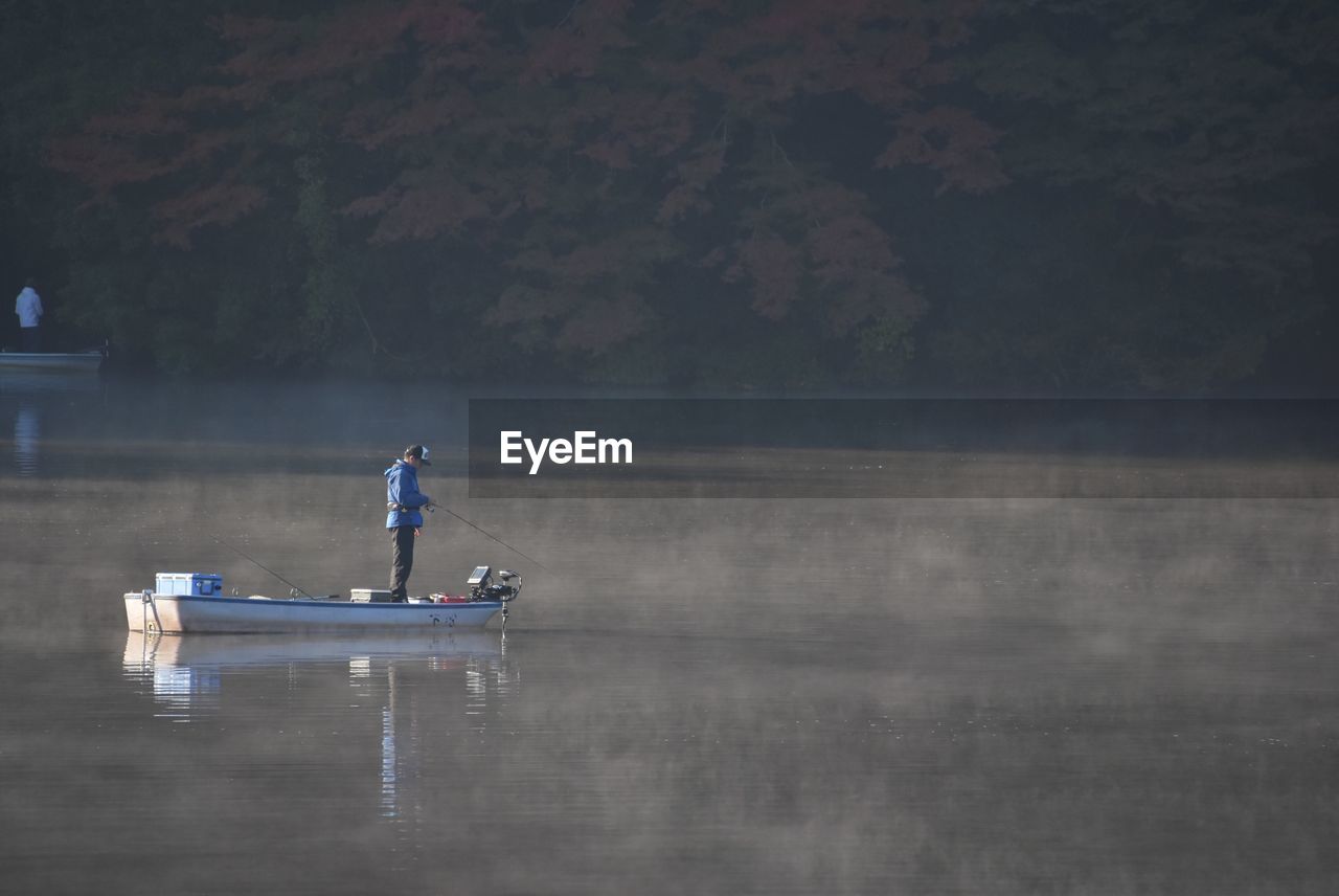 Man standing on boat in lake