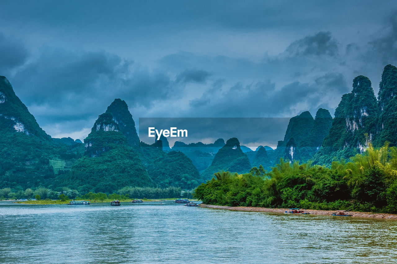 SCENIC VIEW OF LAKE AND MOUNTAIN AGAINST DRAMATIC SKY