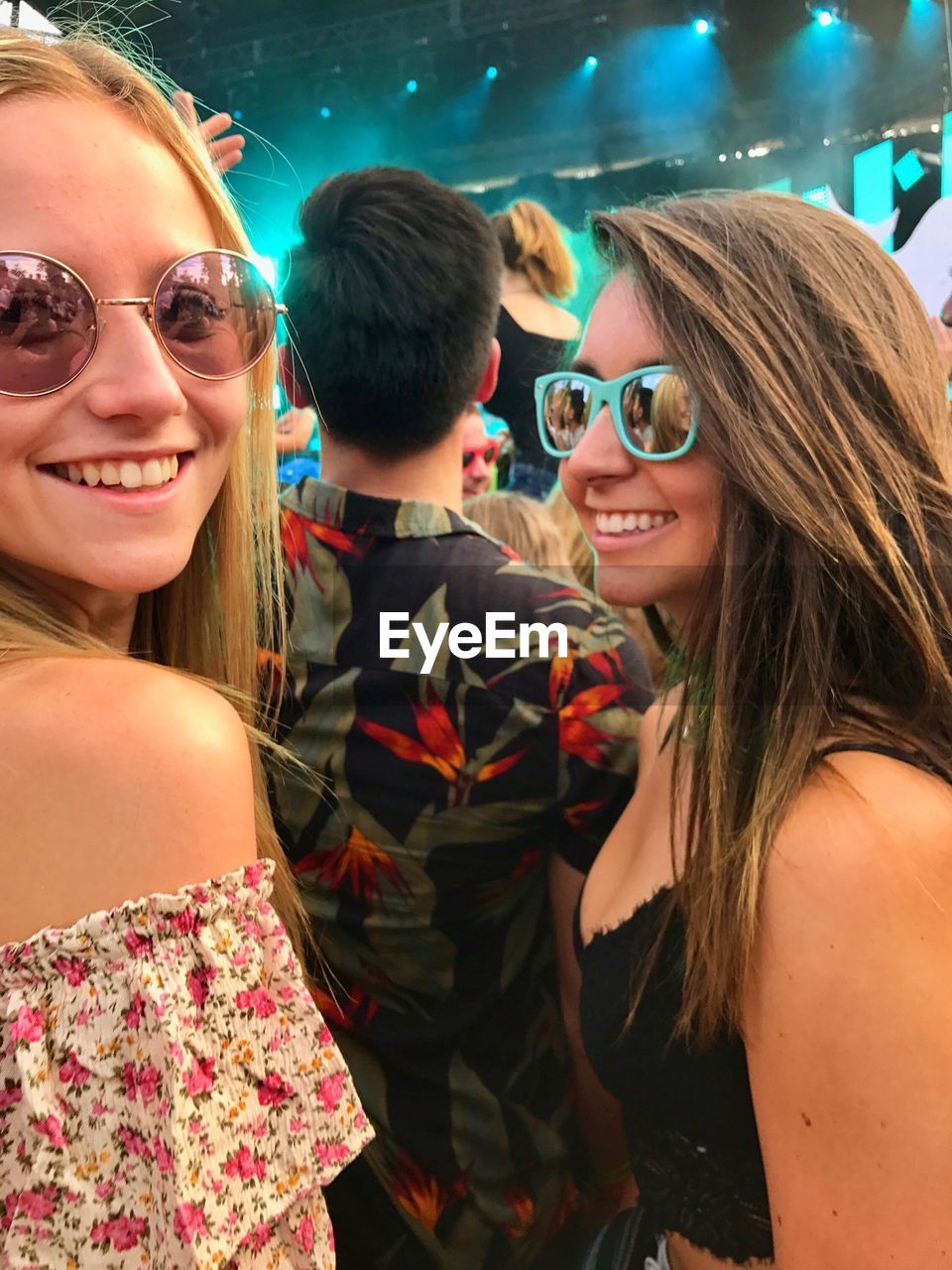 PORTRAIT OF SMILING YOUNG WOMAN WITH SUNGLASSES IN MUSIC CONCERT