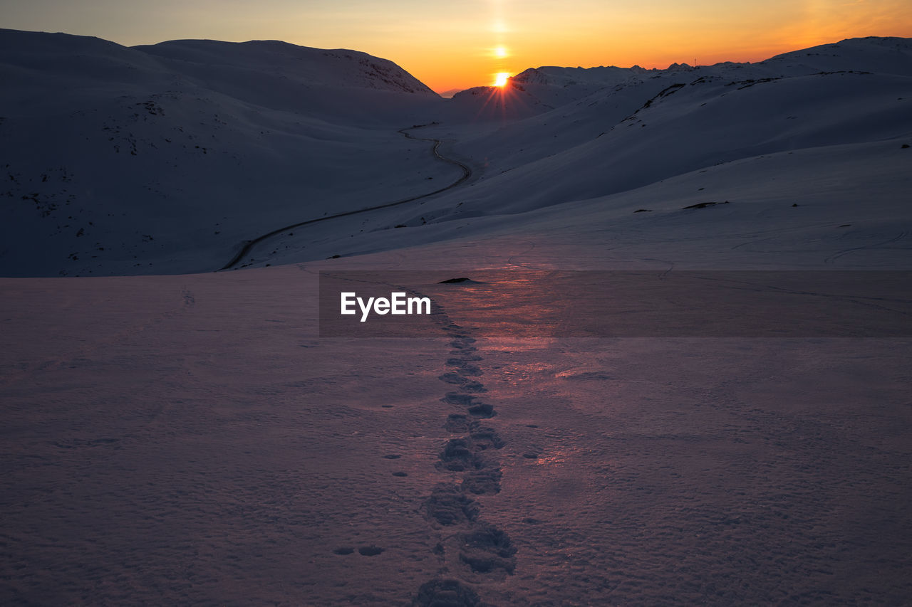 Scenic view of snow field against sky during sunset