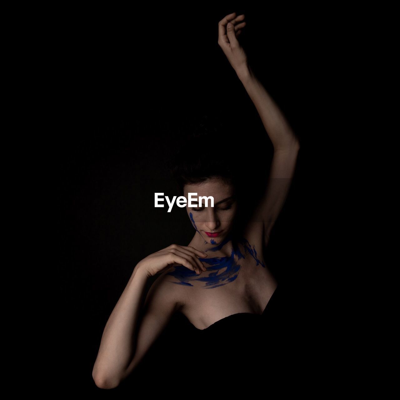 Young woman with body paint against black background