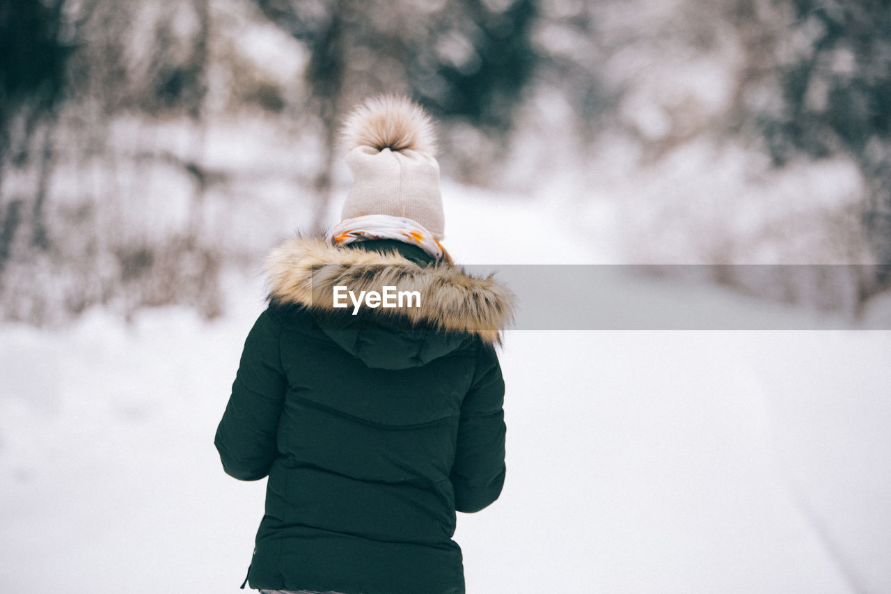 Rear view of woman on snow covered field