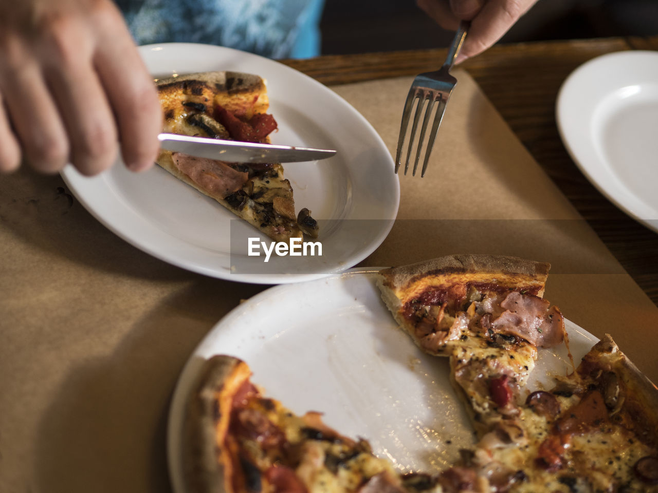 Close-up of person eating pizza in plate