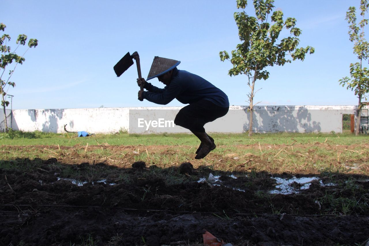 SIDE VIEW OF MAN JUMPING ON FIELD