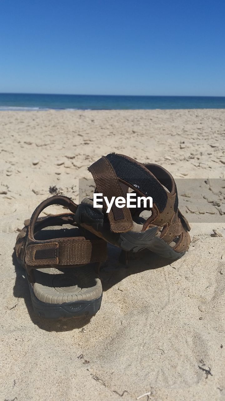 CLOSE-UP OF SHOES ON SANDY BEACH