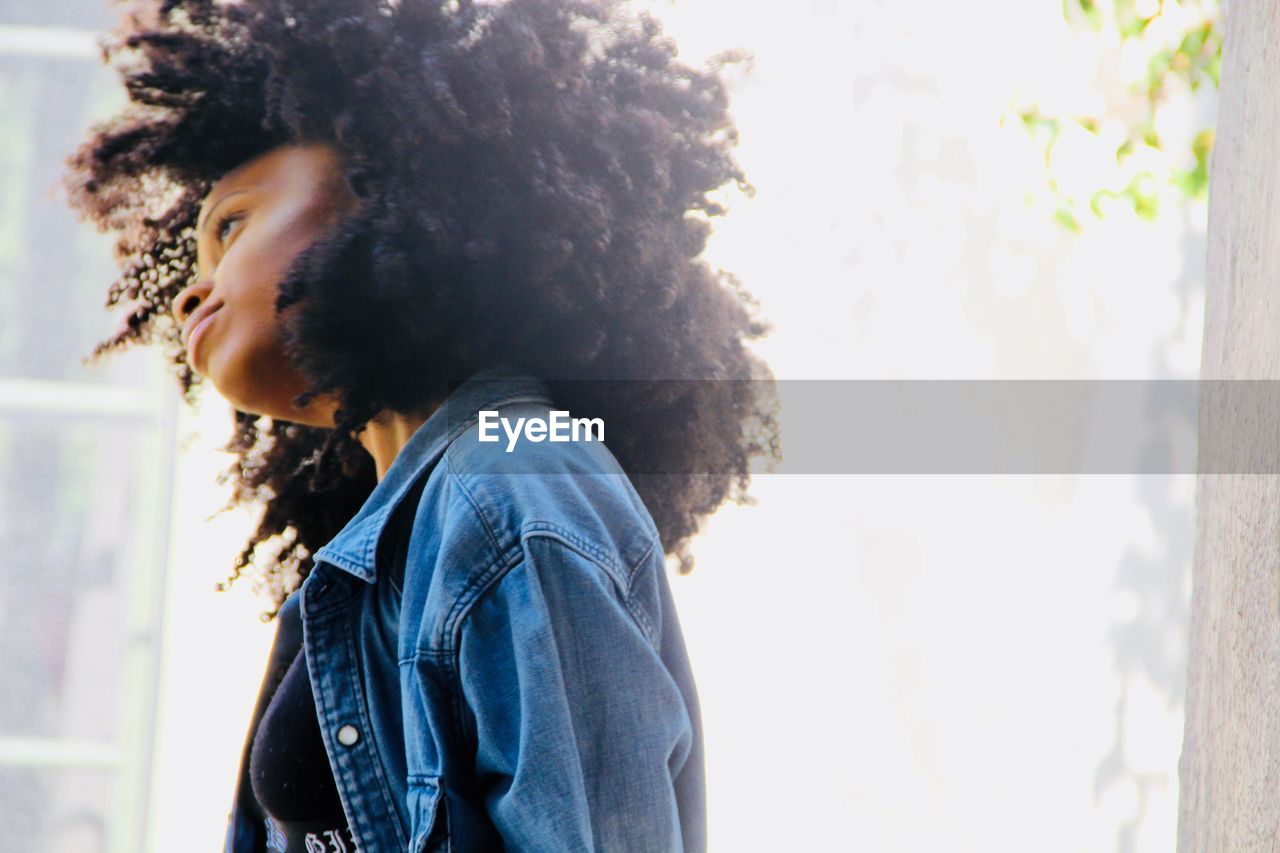 CLOSE-UP OF YOUNG WOMAN STANDING AGAINST SKY