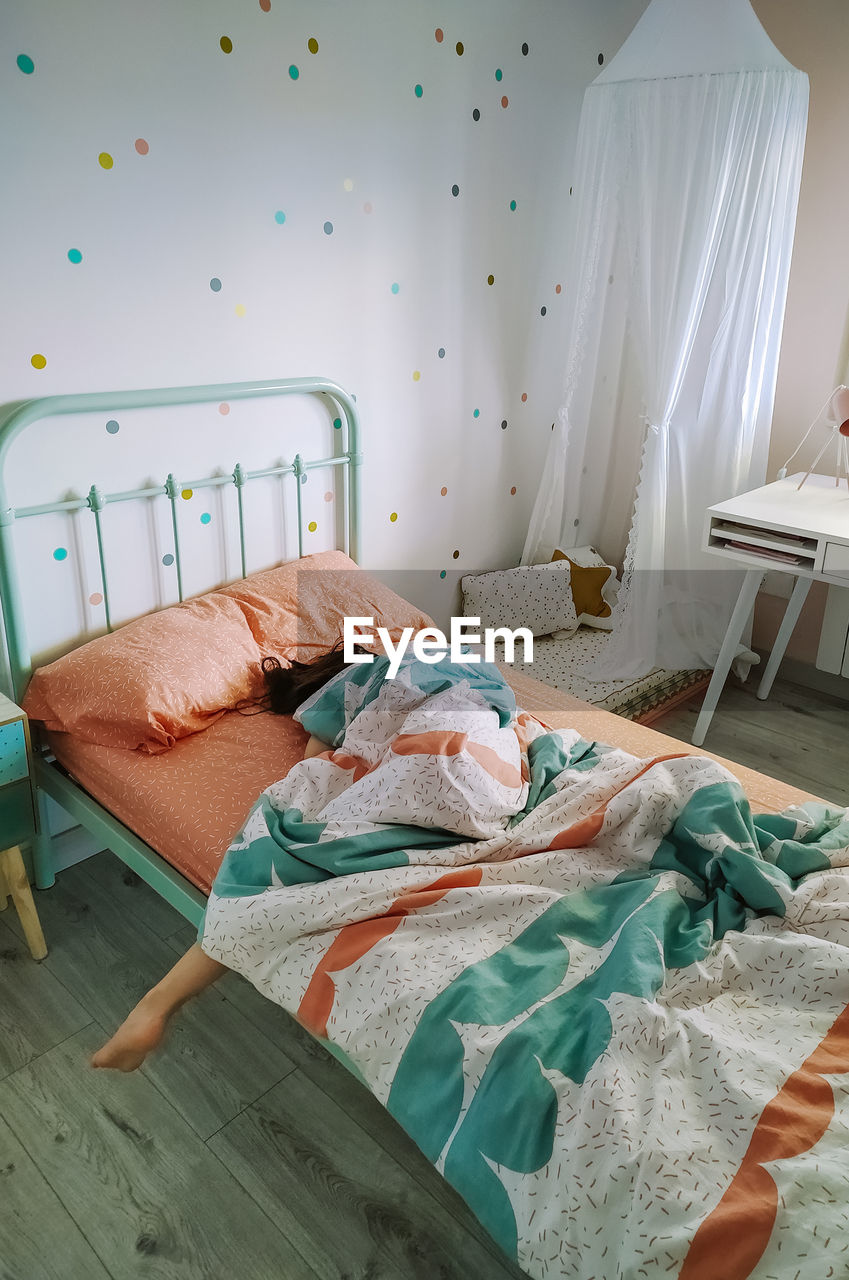 High angle view of girl sleeping on bed at home