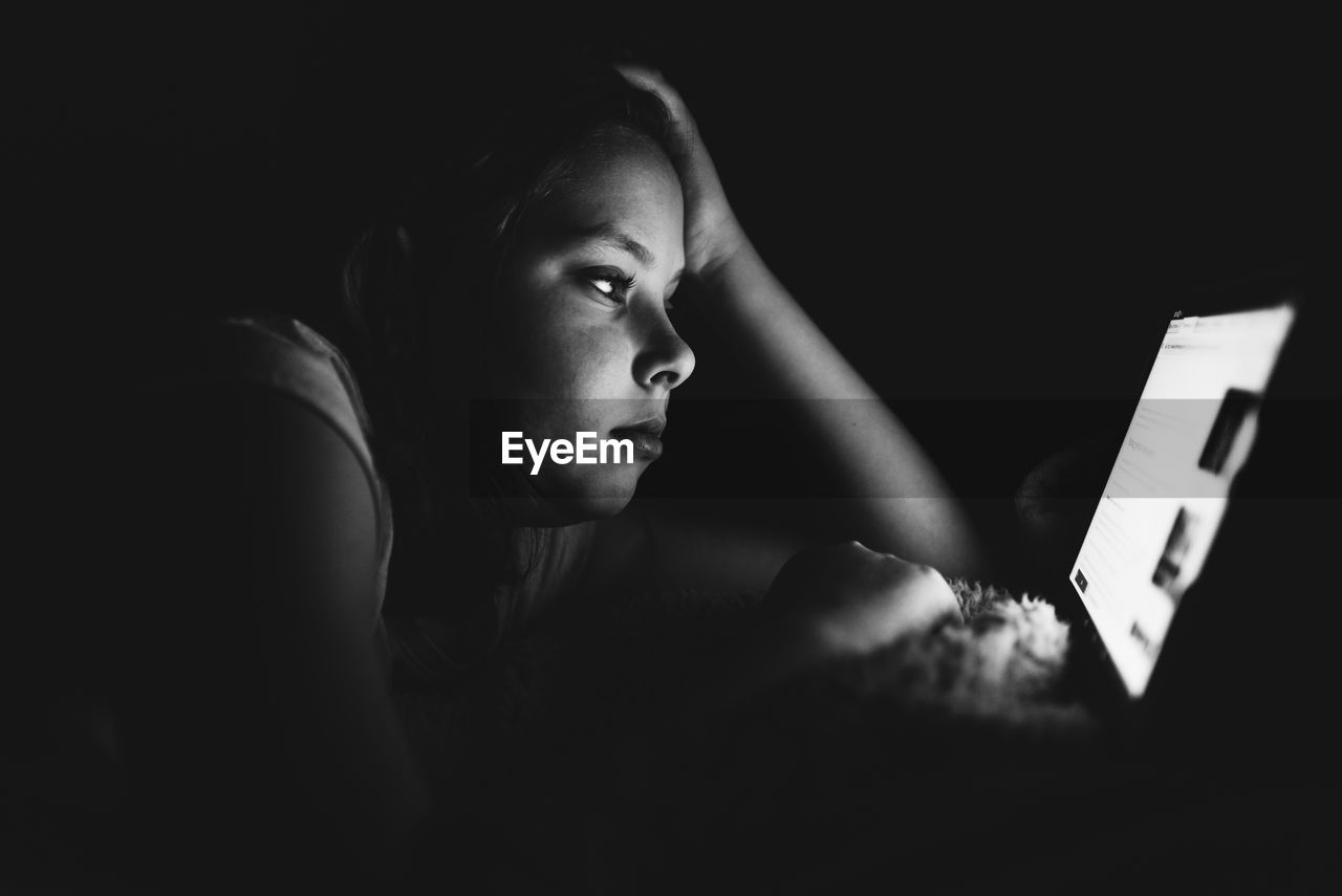 Girl using digital tablet against black background