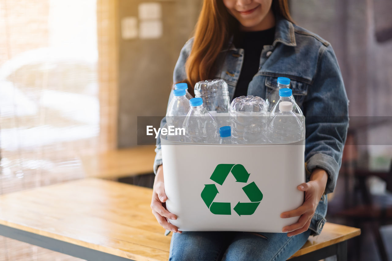 midsection of woman drinking water from bottle