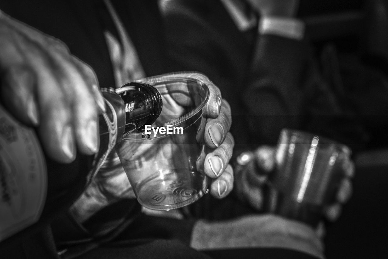 CLOSE-UP OF A HAND HOLDING GLASS OF A MAN