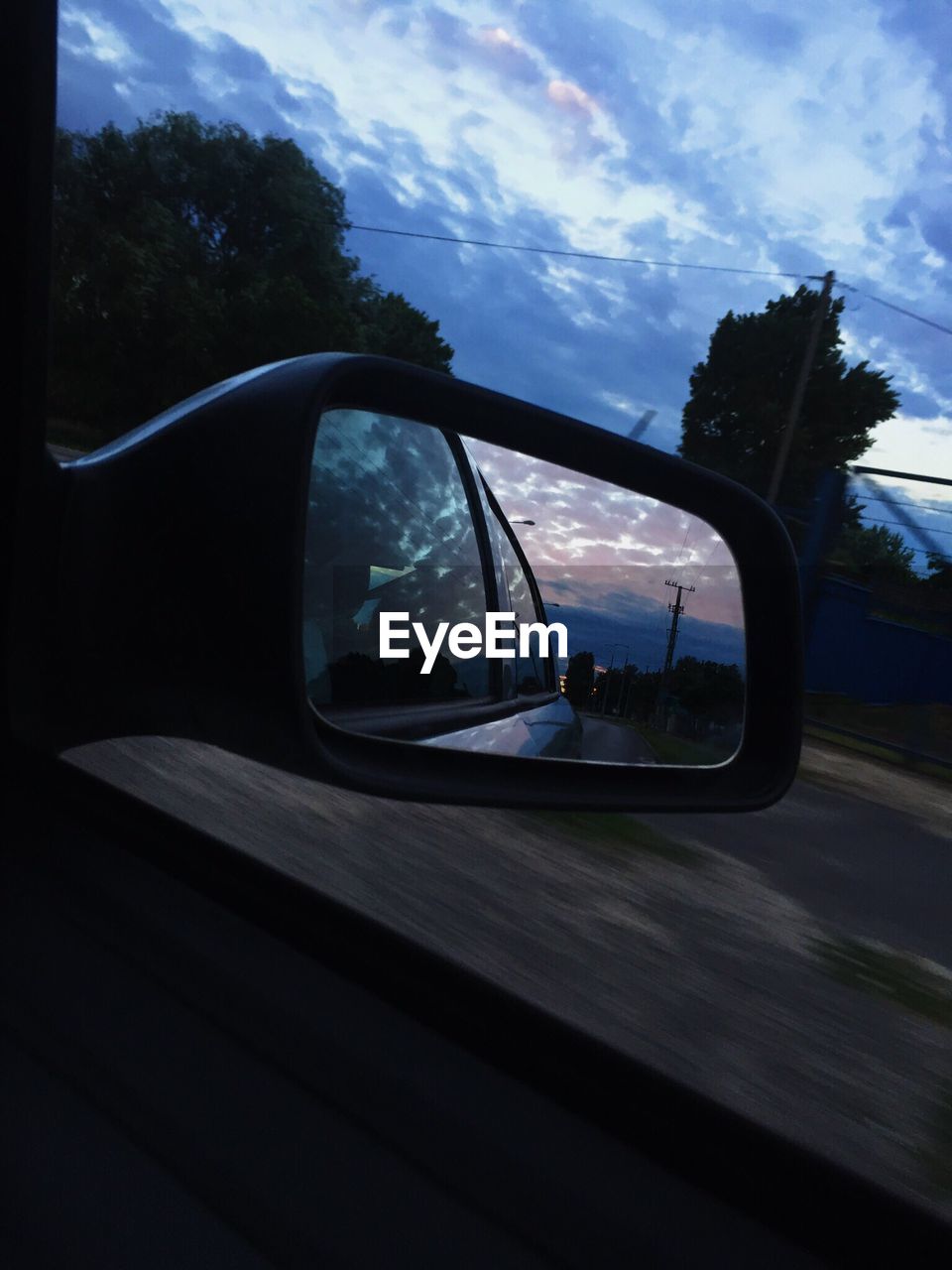 REFLECTION OF CAR ON SIDE-VIEW MIRROR OF ROAD