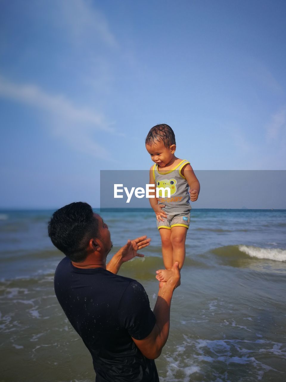 FATHER AND SON ON BEACH AGAINST SKY