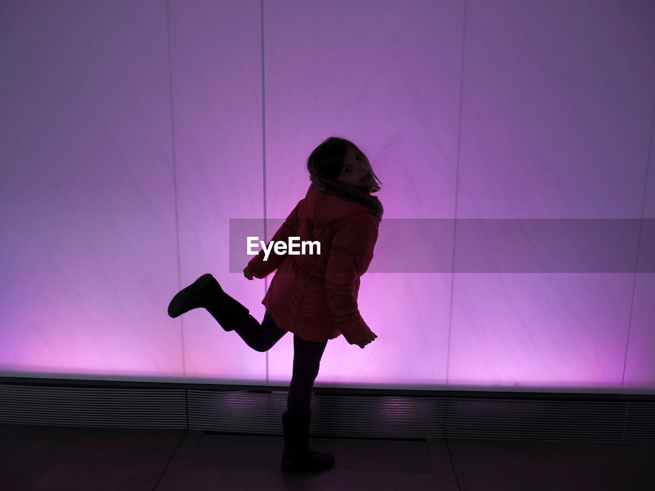 Portrait of girl dancing against illuminated wall