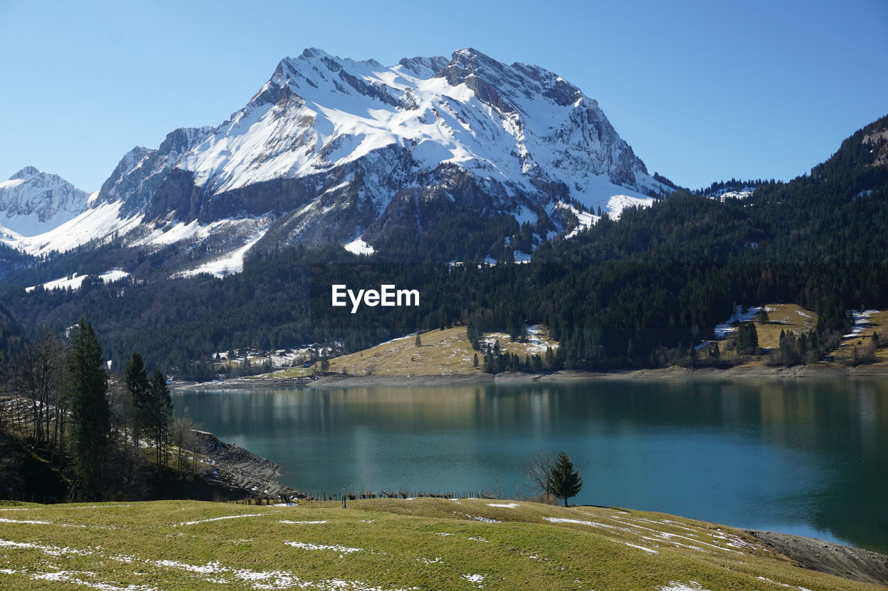 Scenic view of lake by snowcapped mountains against sky