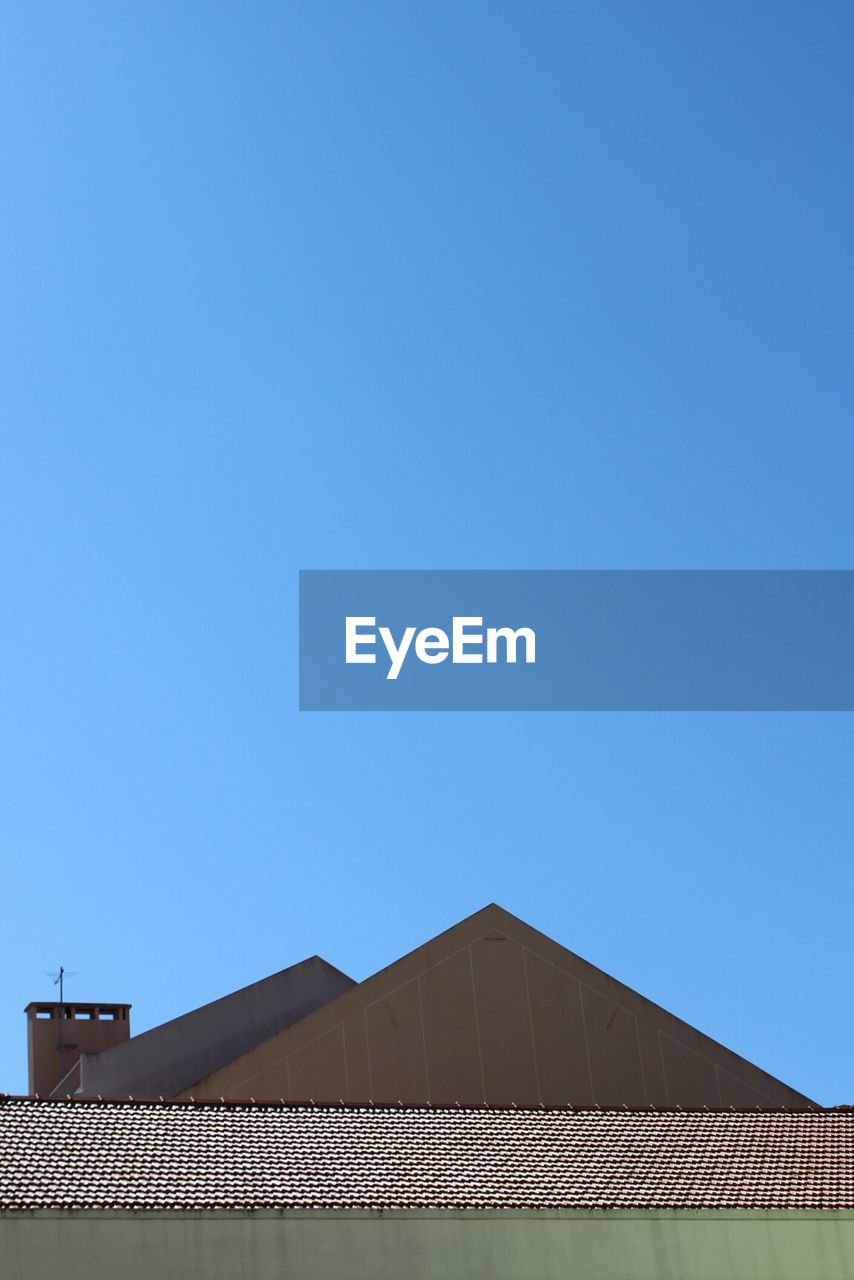 LOW ANGLE VIEW OF BUILDING ROOF AGAINST CLEAR BLUE SKY