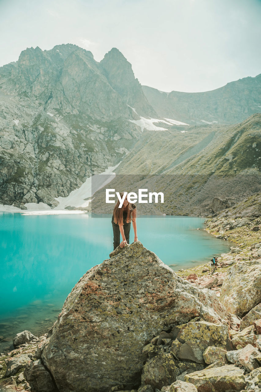 PEOPLE STANDING ON ROCK AGAINST SKY