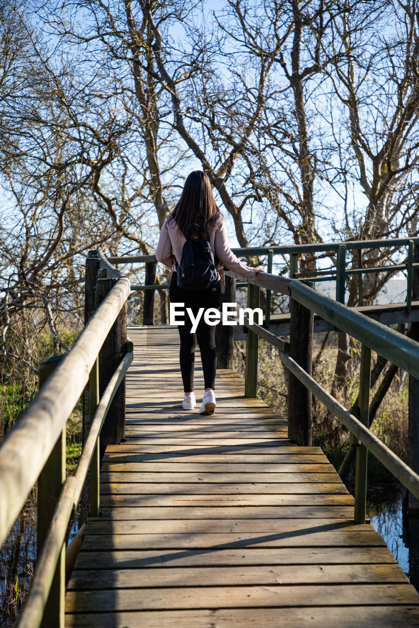 Beautiful woman hiking on a wooden runway above a swamp back shot person