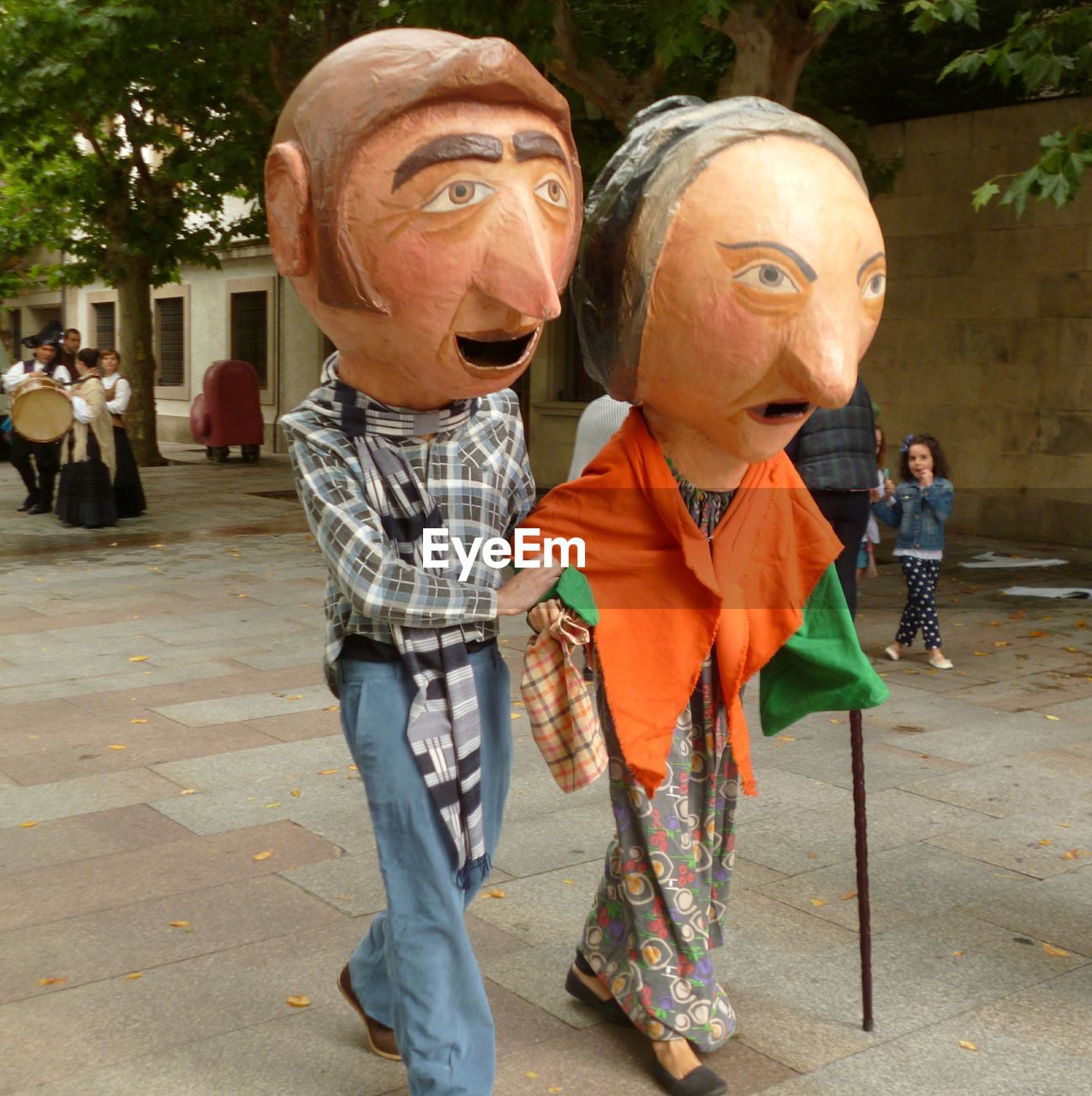 Couple wearing large costumes while walking on footpath