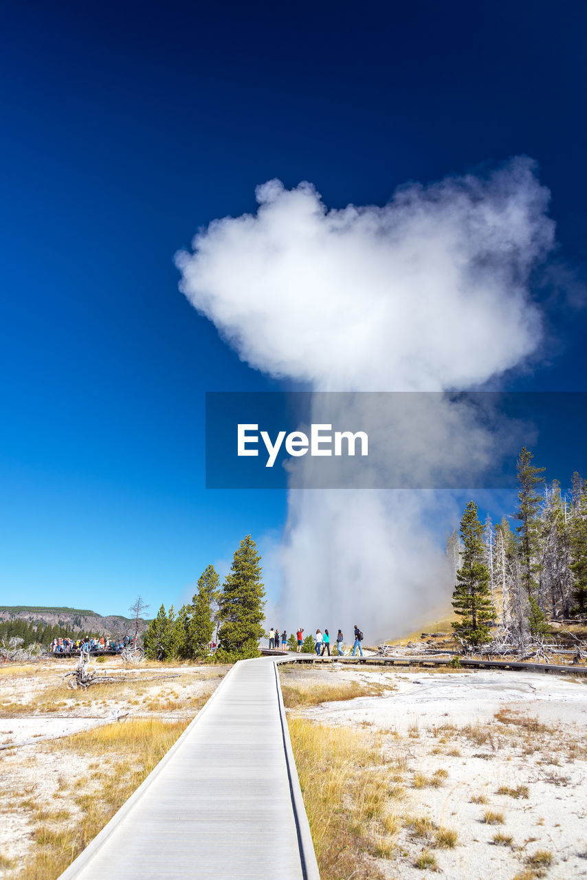 Steam emitting from landscape against blue sky