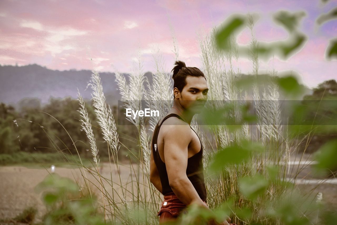 Young man standing on field during sunset