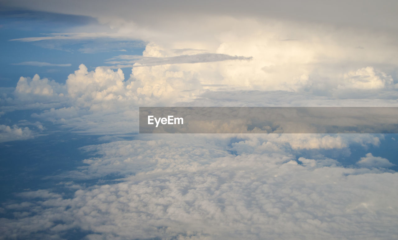 sky, cloud, aerial view, environment, horizon, cloudscape, nature, beauty in nature, scenics - nature, no people, landscape, airplane, sunlight, plain, outdoors, day, flying, tranquility, atmosphere, mountain, travel, air vehicle, high angle view, idyllic, tranquil scene, transportation, high up, fluffy, blue, dramatic sky, overcast, white, mountain range