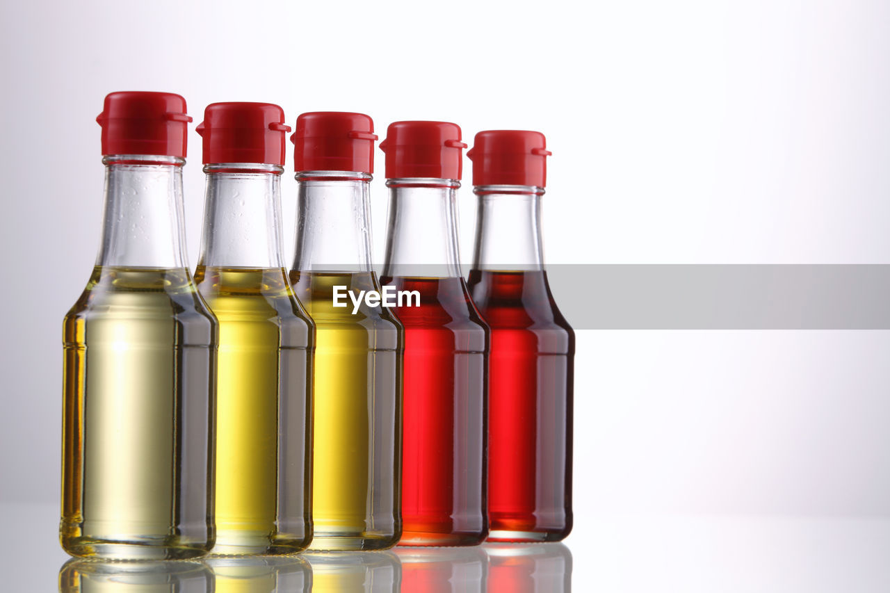 Close-up of cooking oil in bottles against white background