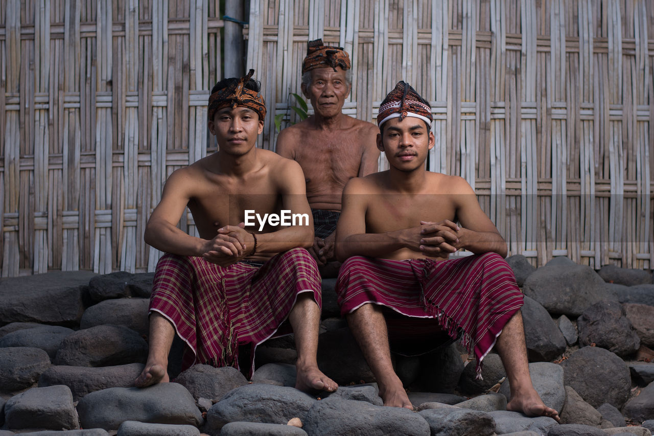 PORTRAIT OF YOUNG MEN SITTING OUTDOORS