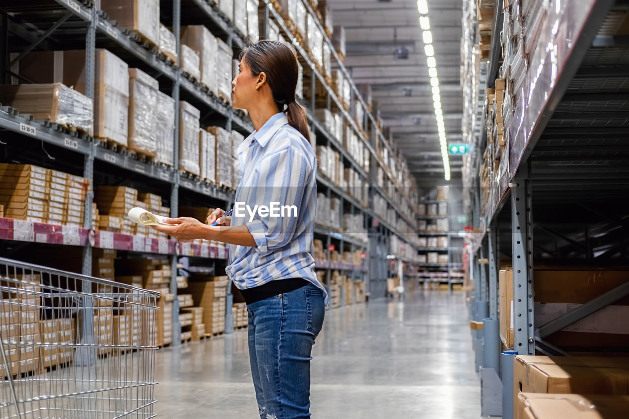 Woman writing while standing in warehouse