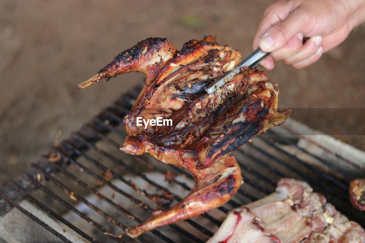 CLOSE-UP OF HAND HOLDING BARBECUE GRILL