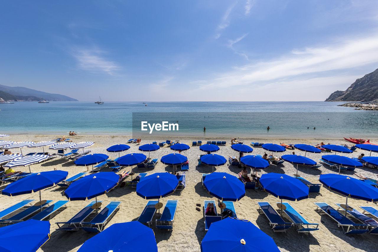Italy, liguria, monterosso al mare, rows of deck chairs and umbrellas on sandy beach along cinque terre