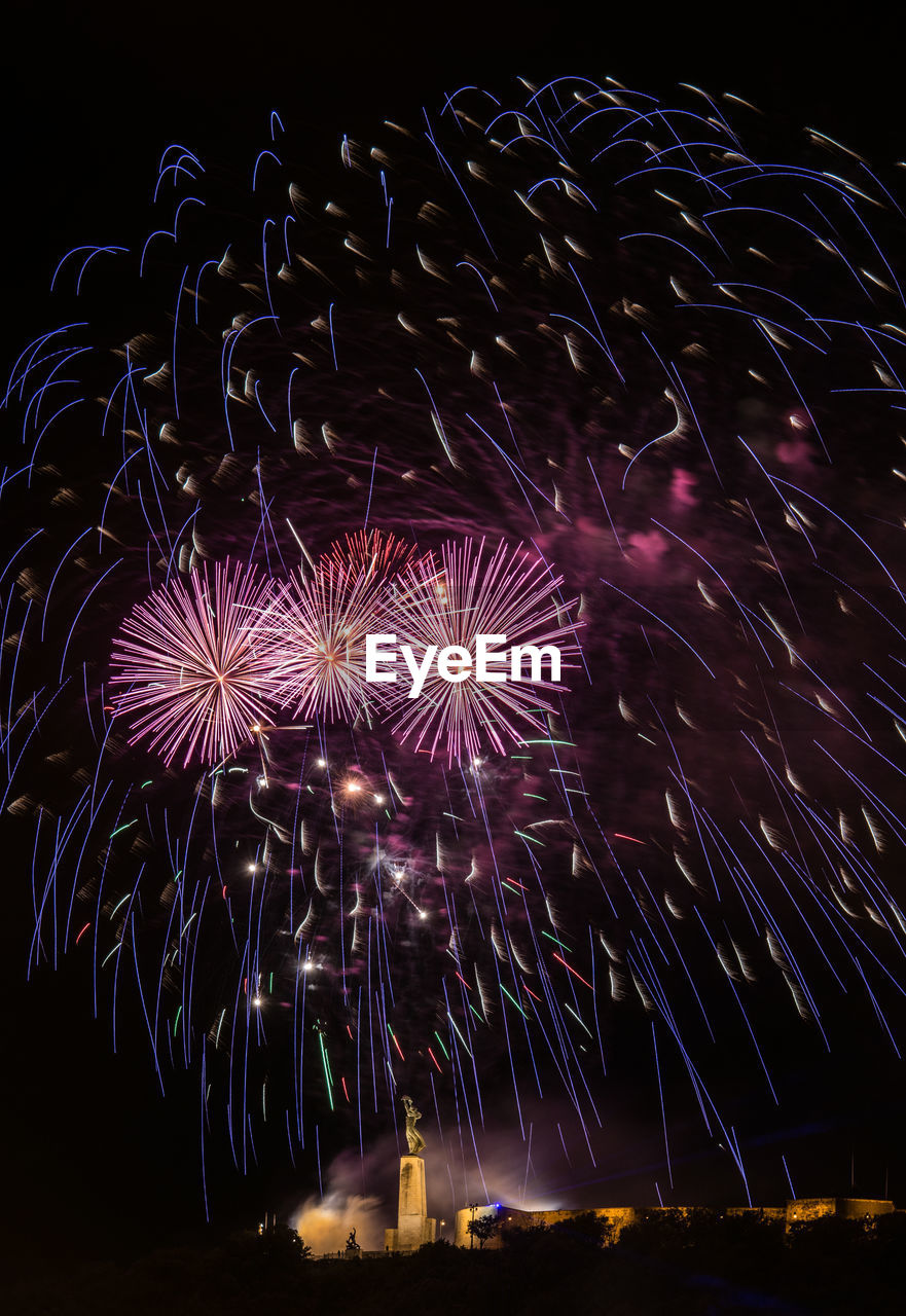 Low angle view of firework display over city at night