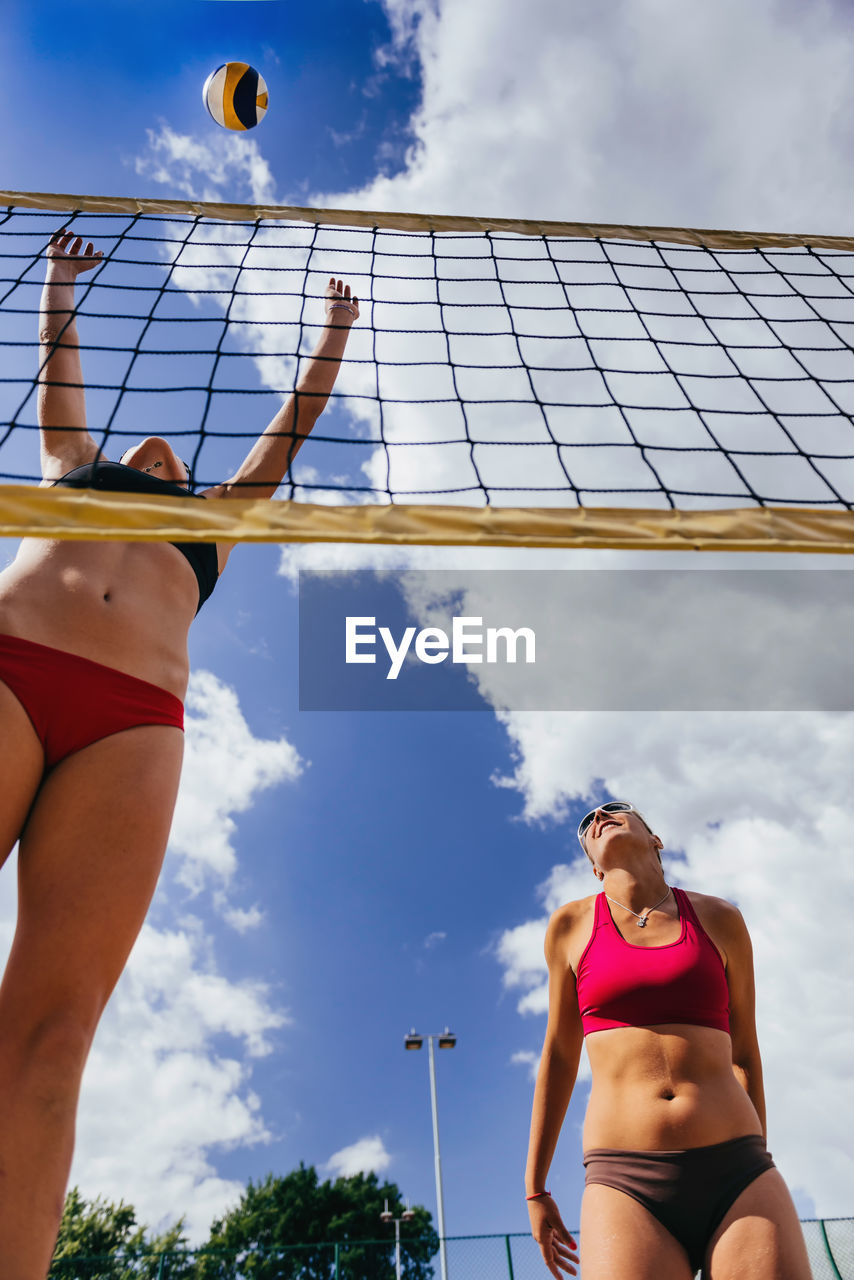 Low angle view of young woman playing volleyball