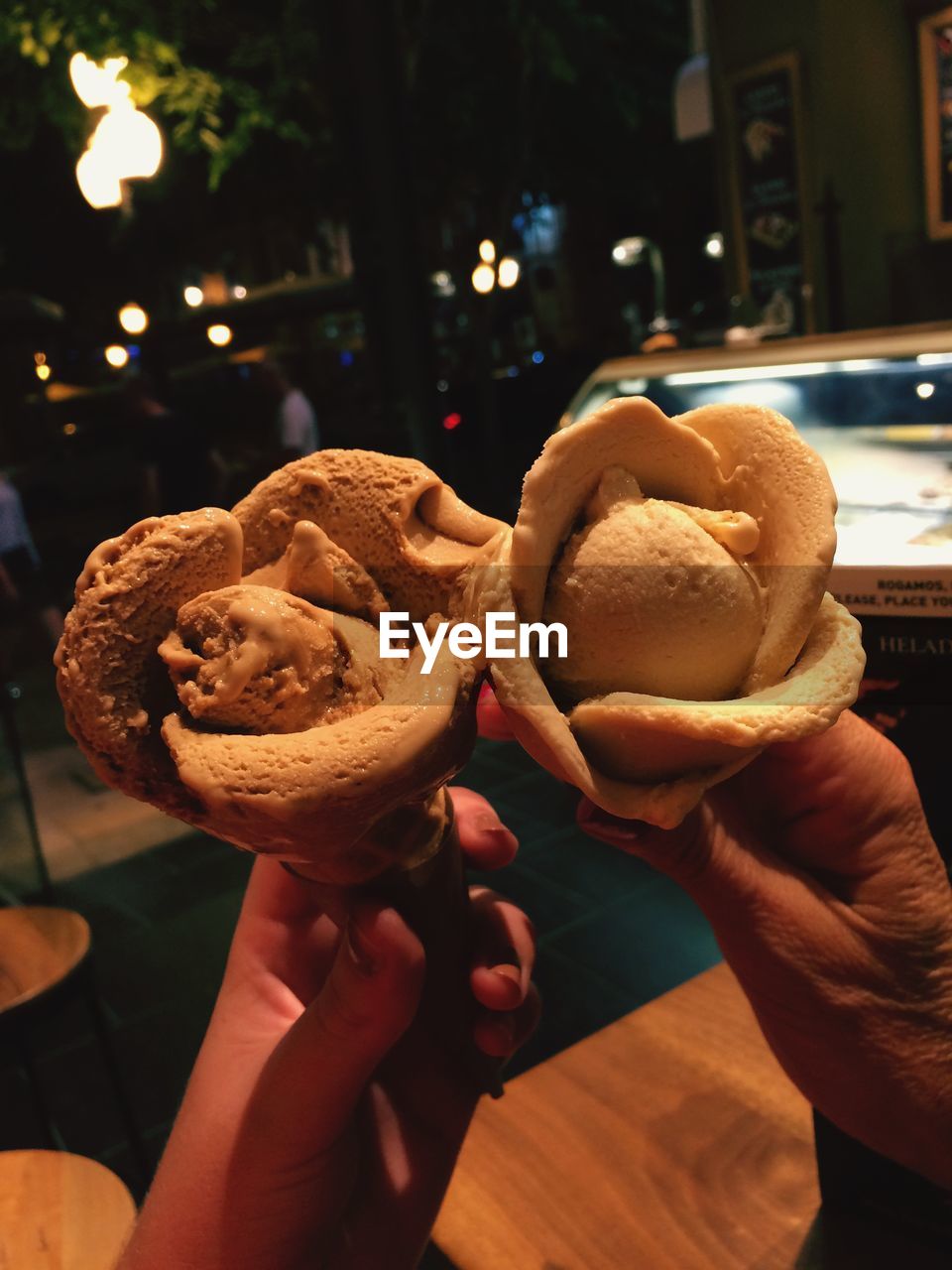 Cropped hand holding caramel ice creams at night