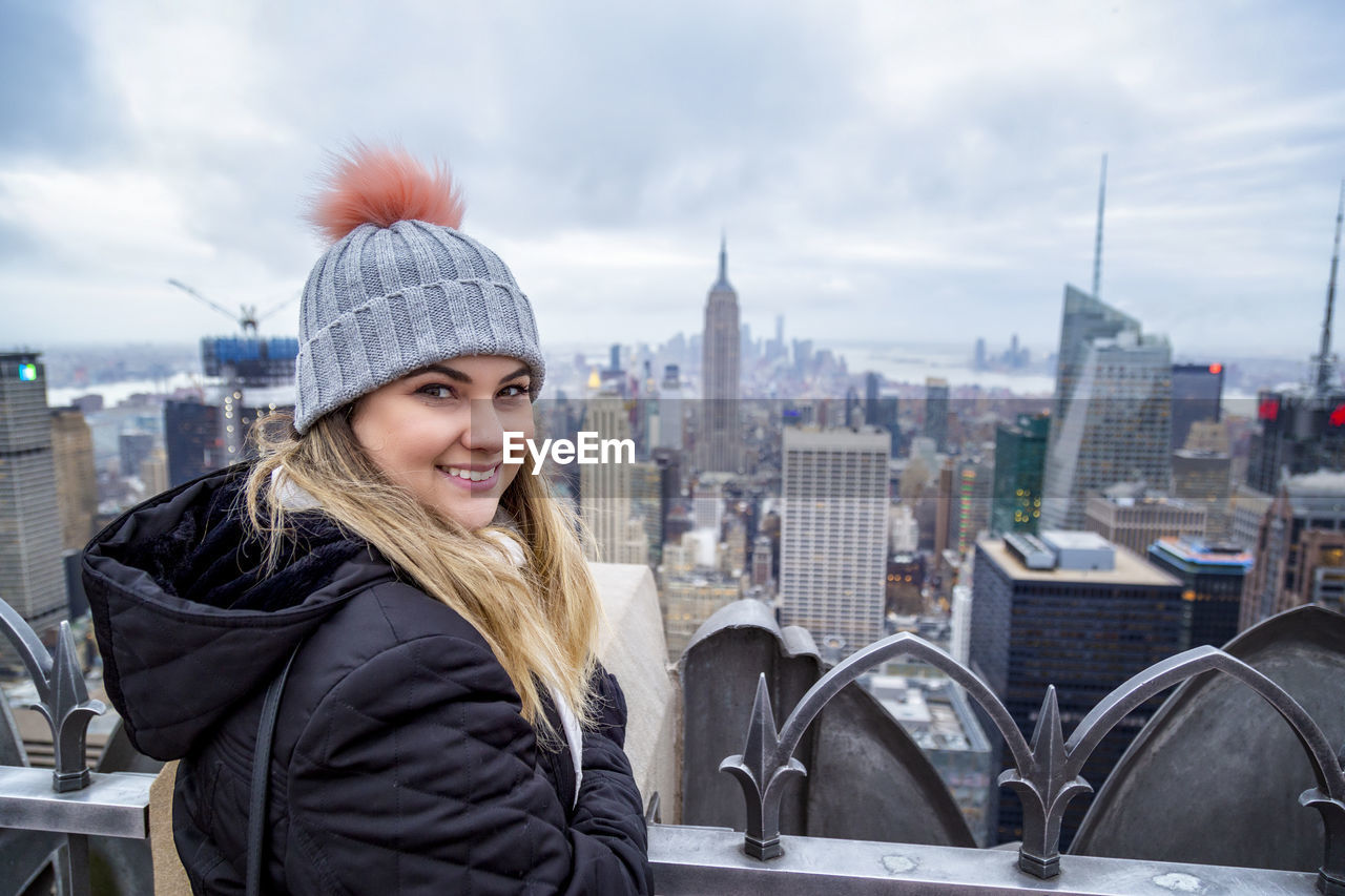 PORTRAIT OF SMILING YOUNG WOMAN IN CITY