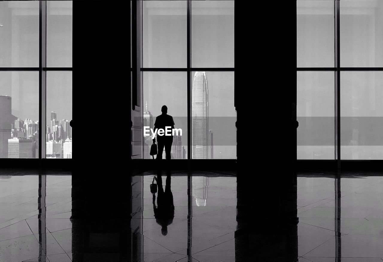 Silhouette man looking at international finance centre through window