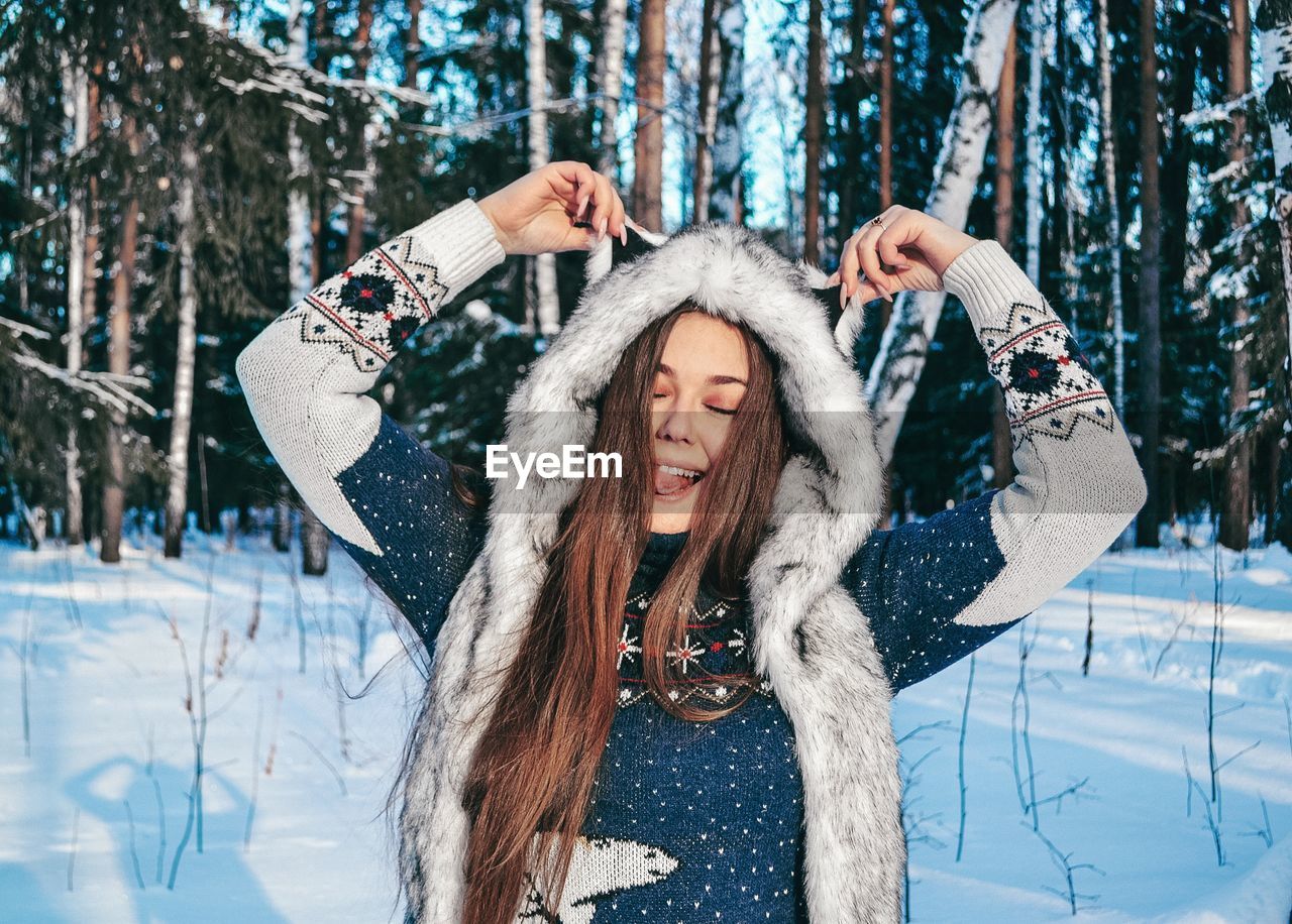 Woman with eyes closed standing in forest during winter