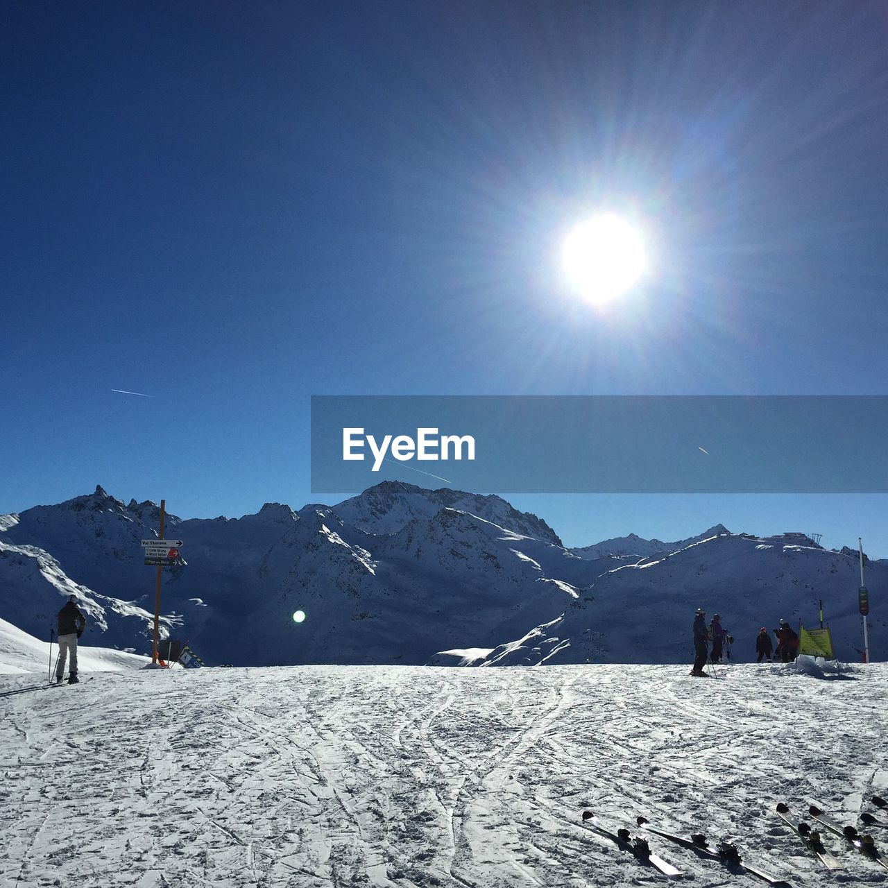People skiing on snowy mountains against blue sky during sunny day