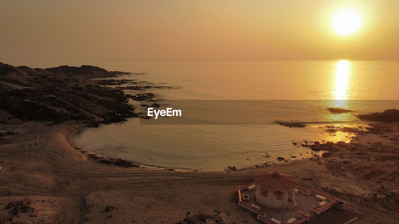 water, sea, sunset, sky, land, beach, scenics - nature, sun, beauty in nature, nature, horizon, tranquility, coast, horizon over water, ocean, dawn, tranquil scene, sunlight, sand, evening, shore, travel destinations, travel, idyllic, wave, no people, environment, landscape, seascape, coastline, outdoors, reflection, vacation, trip, holiday, orange color, tourism, body of water, non-urban scene