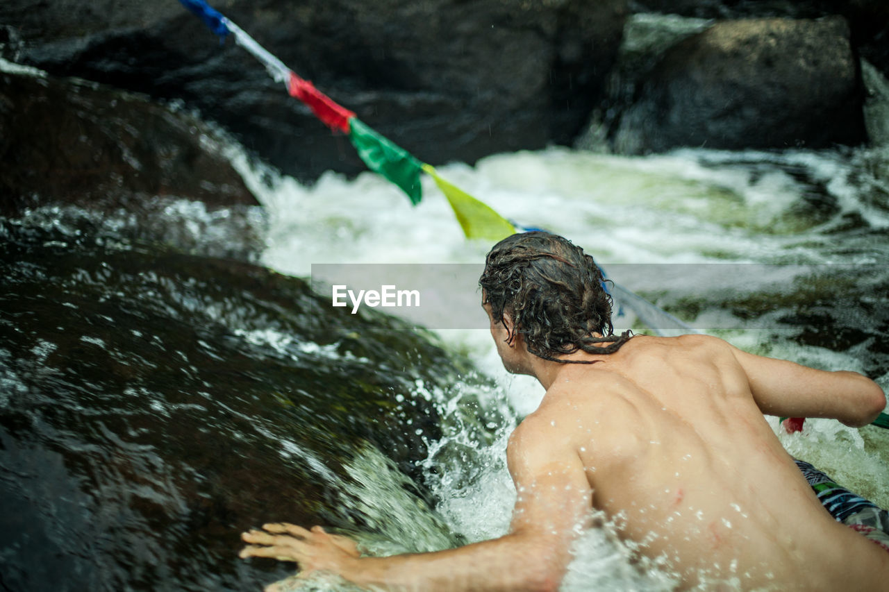 Rear view of shirtless man in river