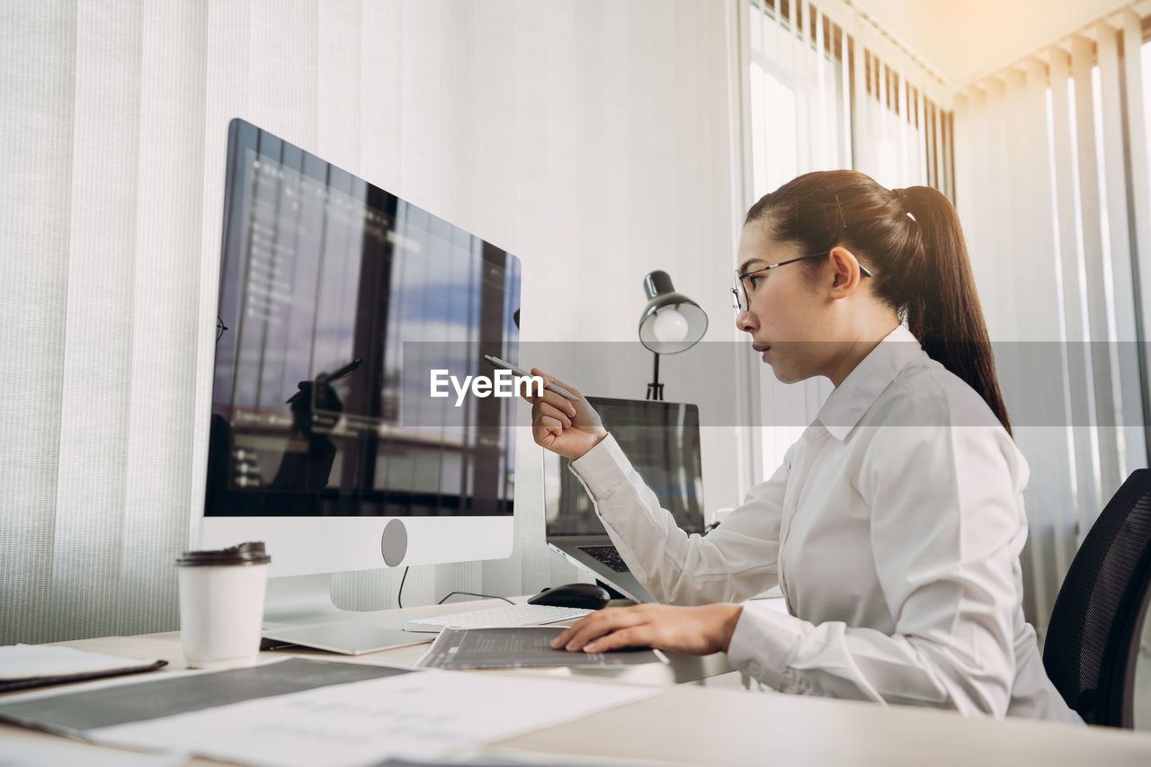 YOUNG WOMAN USING MOBILE PHONE IN OFFICE