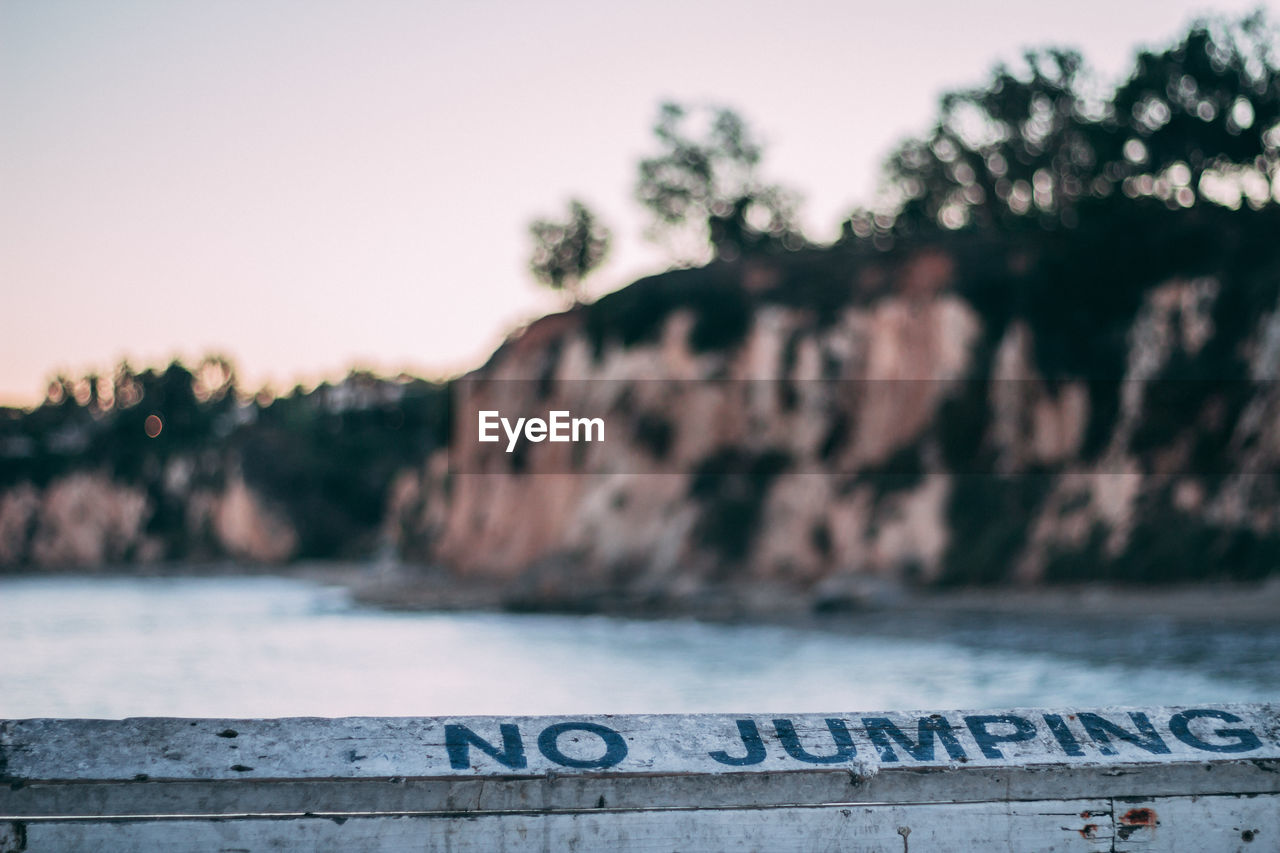 CLOSE-UP OF TEXT ON RETAINING WALL AGAINST SUNSET SKY