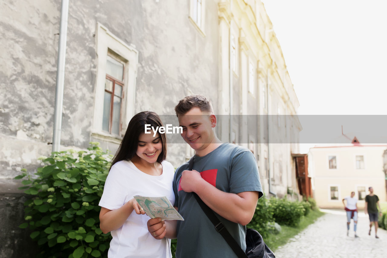 Couple of handsome heterosexual tourists in love looking at city map to understand how to find place