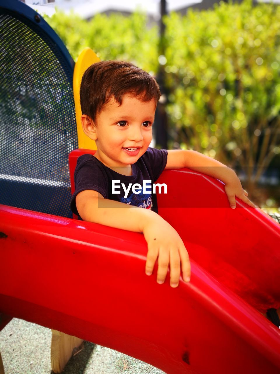Smiling cute boy sitting on slide