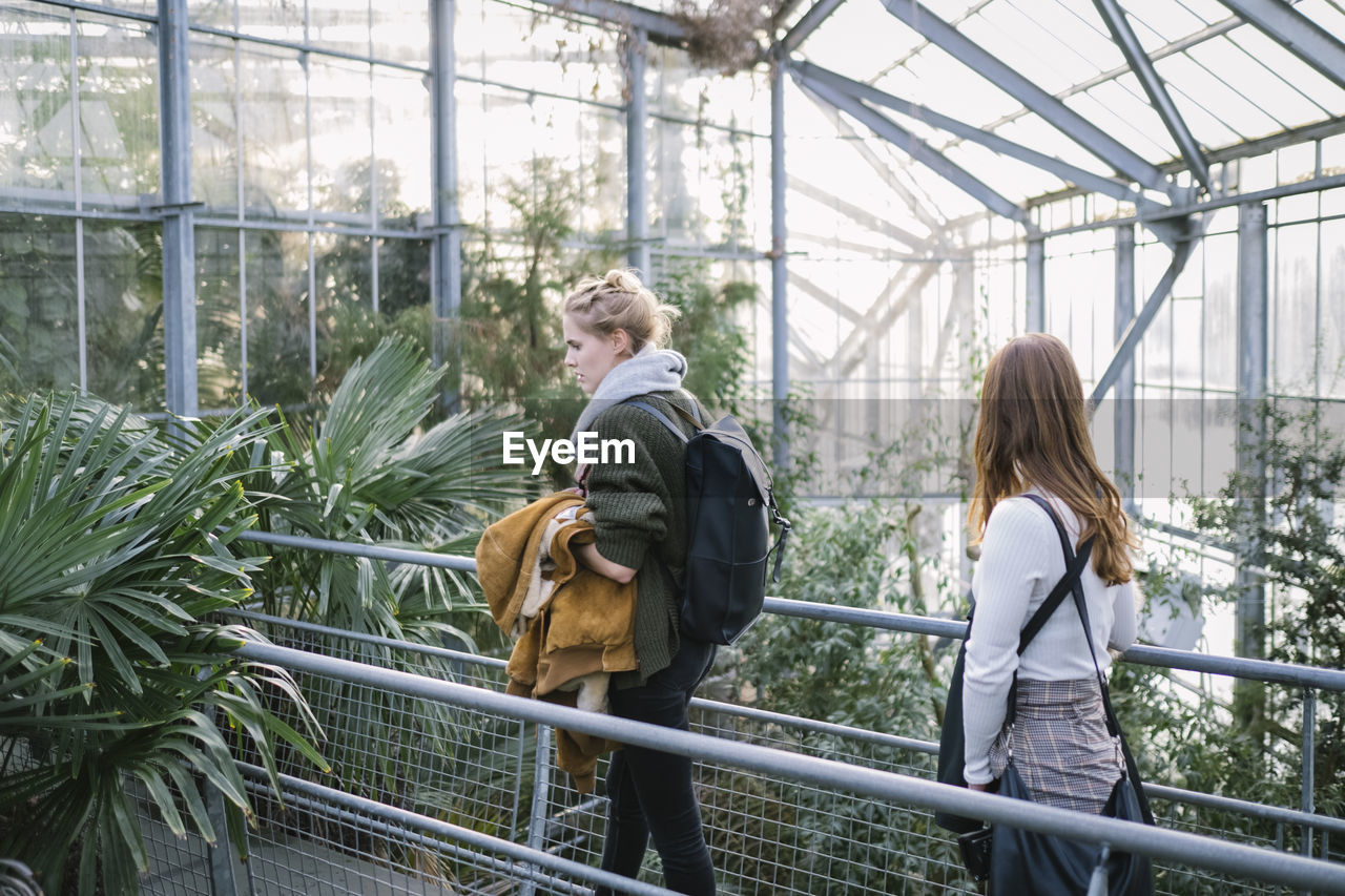 Women walking amidst plants in greenhouse
