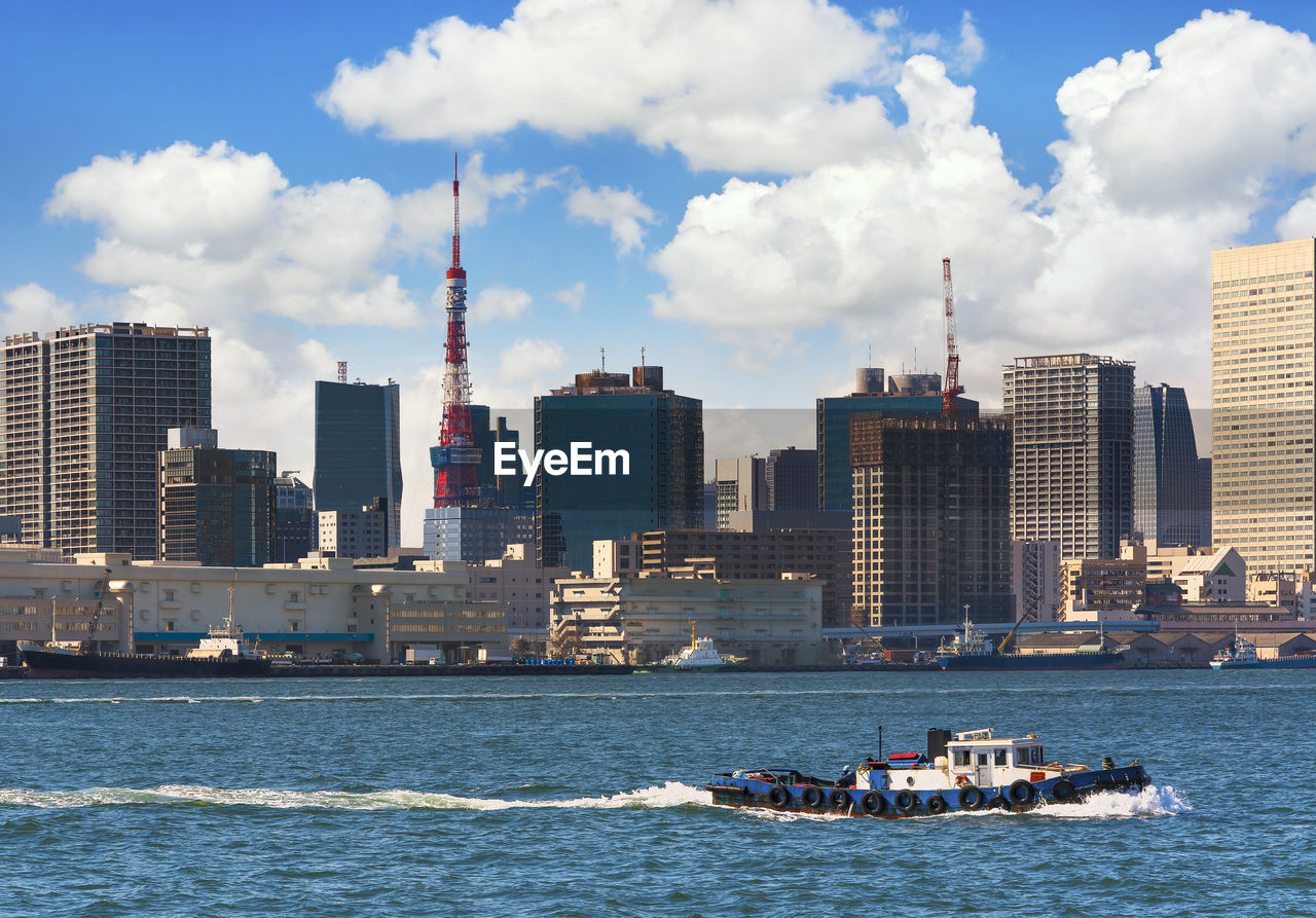 Japanese tugboats sailing in front of the hinode pier on tokyo port with tokyo tower.