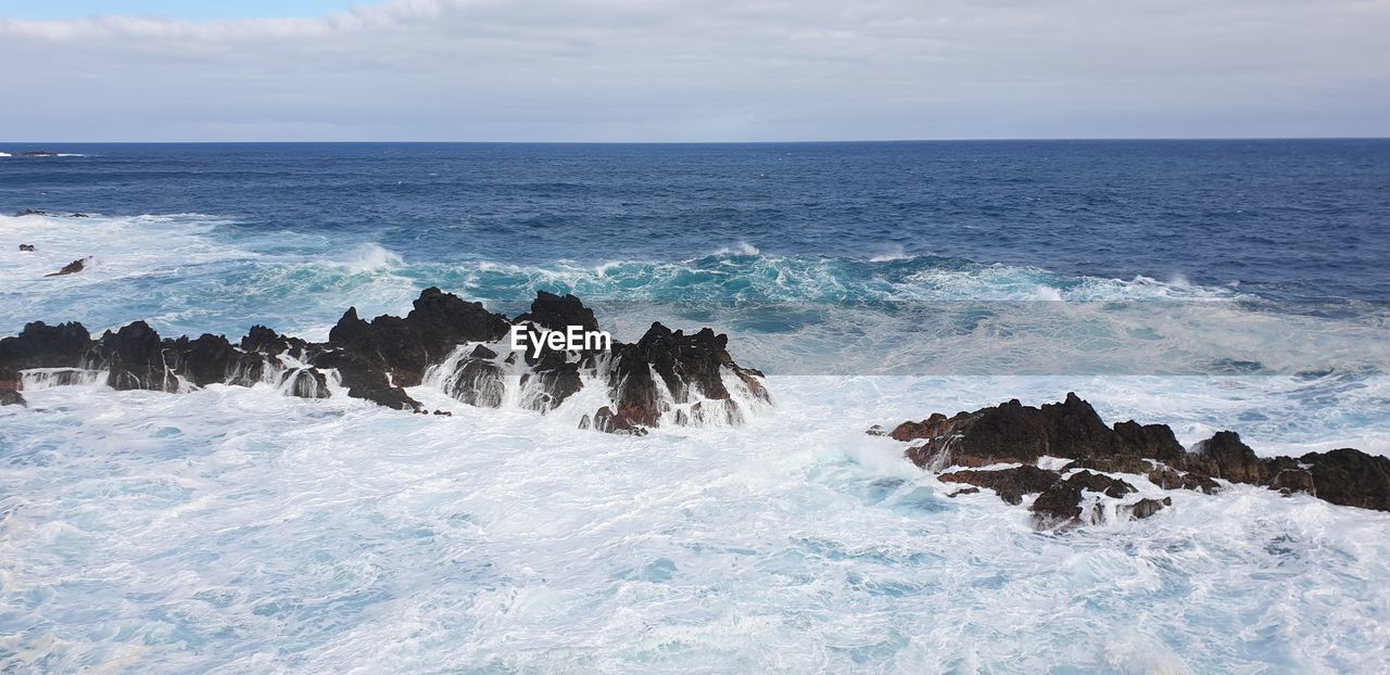 SCENIC VIEW OF ROCKS ON SHORE AGAINST SKY