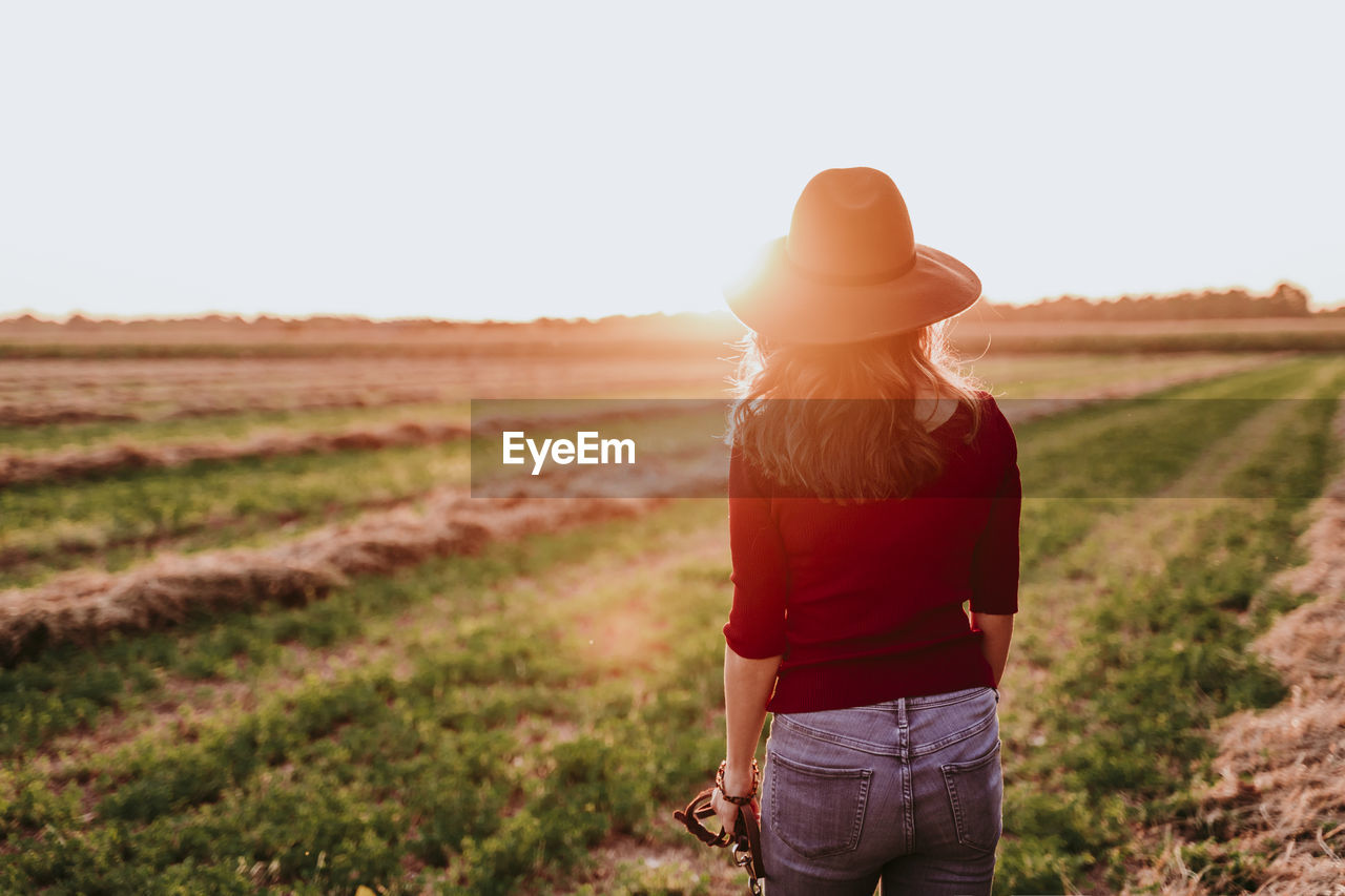 Rear view of woman standing on landscape during sunset